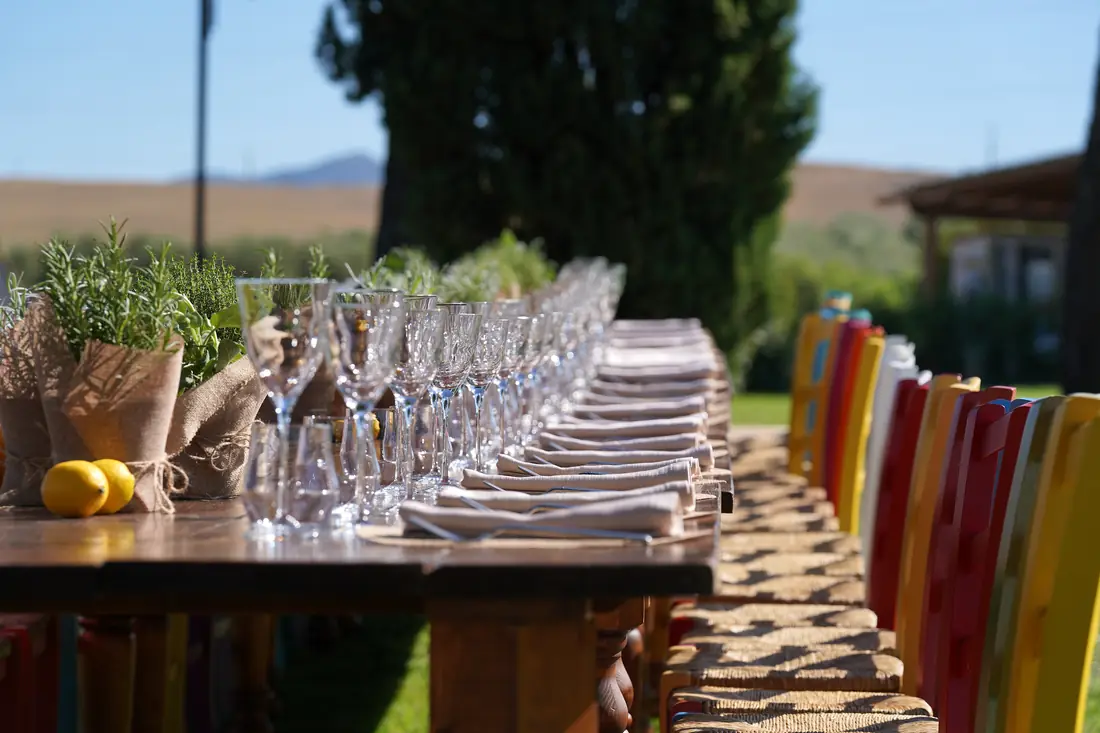 Rustic long table with colourful chairs, rosemary and lemons