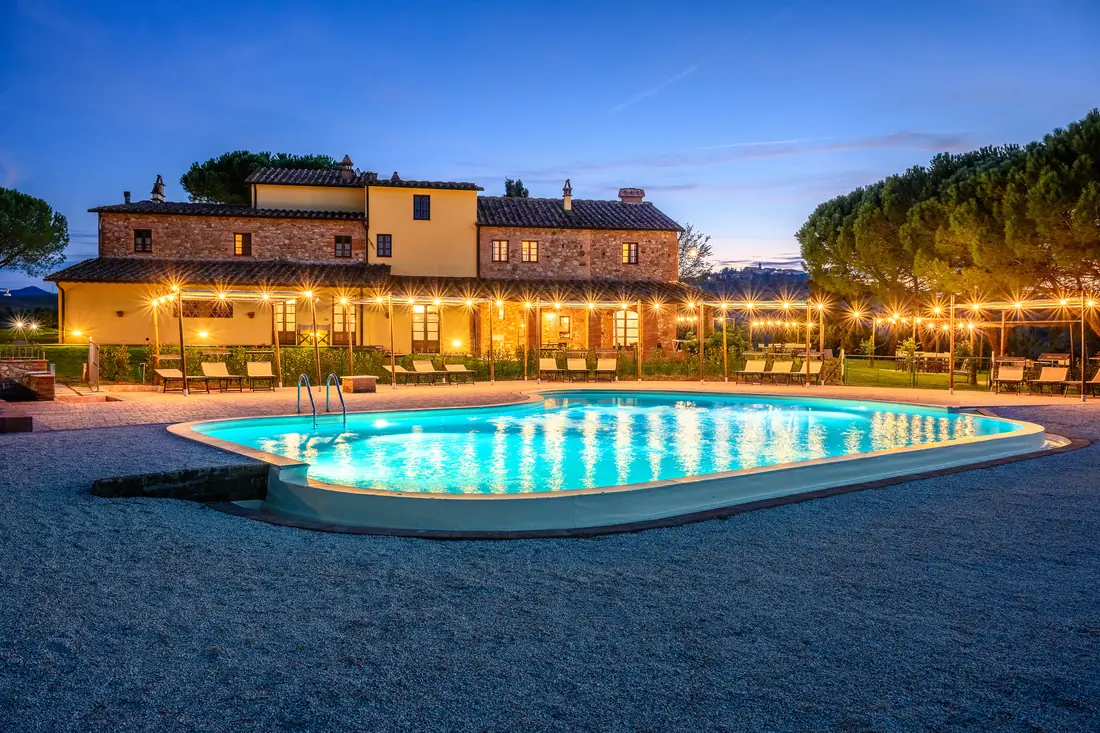 The illuminated pool and farmhouse of Casa d’Era at dusk
