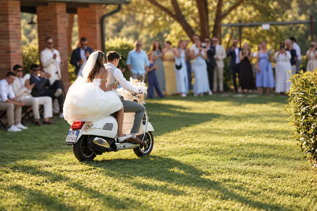 The newlyweds leaving on a Vespa as the guests cheer